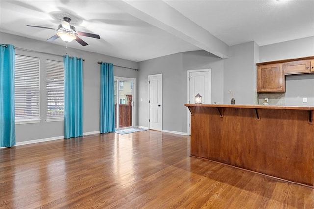 kitchen featuring a kitchen bar, hardwood / wood-style floors, ceiling fan, kitchen peninsula, and decorative backsplash