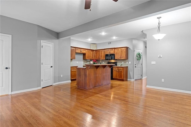 kitchen featuring pendant lighting, light hardwood / wood-style flooring, a center island, and decorative backsplash