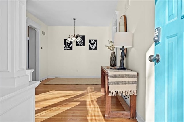 entryway featuring visible vents, a notable chandelier, baseboards, and wood finished floors