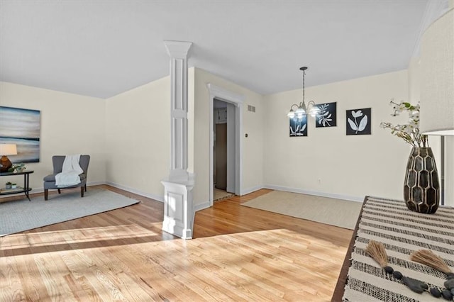 interior space with a chandelier, decorative columns, baseboards, and wood finished floors