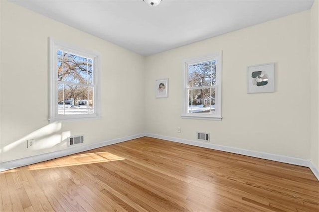 spare room featuring visible vents, baseboards, and wood finished floors