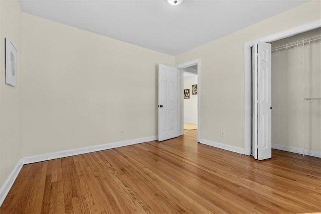 unfurnished bedroom with a closet, baseboards, and light wood finished floors