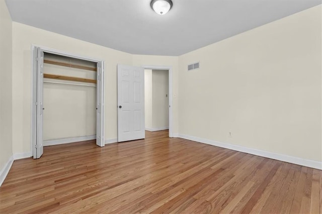 unfurnished bedroom featuring baseboards, a closet, visible vents, and light wood-style floors