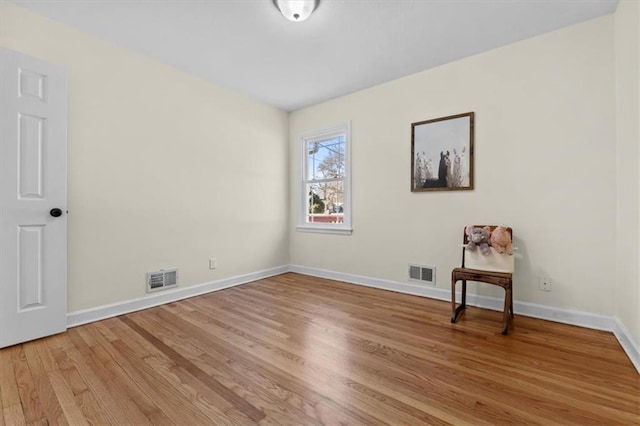 spare room with light wood-style flooring, visible vents, and baseboards