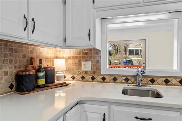 kitchen featuring light countertops, a sink, white cabinetry, and decorative backsplash