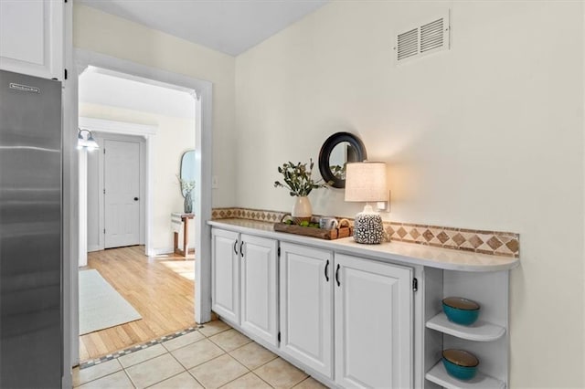 interior space with light tile patterned floors, stainless steel fridge, and visible vents