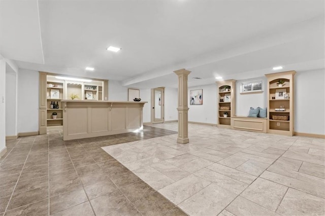 interior space featuring built in shelves, decorative columns, a bar, and baseboards