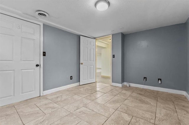 empty room featuring visible vents, a textured ceiling, and baseboards