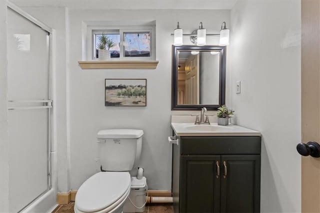 full bathroom with vanity, a shower stall, toilet, and baseboards