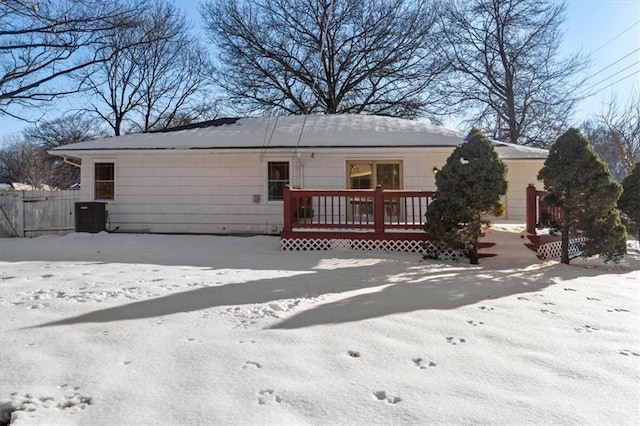 snow covered house featuring fence, a deck, and central AC unit