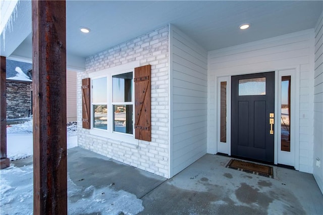 snow covered property entrance with a porch