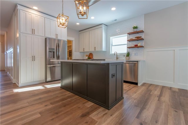 kitchen featuring pendant lighting, a kitchen island, white cabinets, and appliances with stainless steel finishes