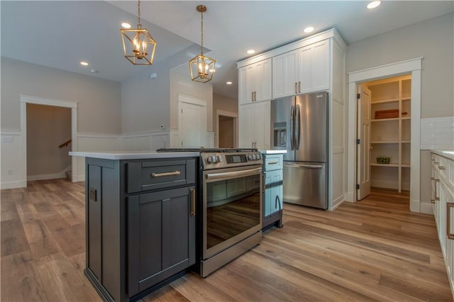 kitchen featuring white cabinetry, hanging light fixtures, light hardwood / wood-style flooring, appliances with stainless steel finishes, and a kitchen island