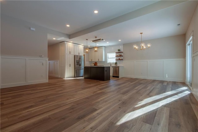 kitchen featuring pendant lighting, hardwood / wood-style flooring, stainless steel appliances, a kitchen island, and a chandelier