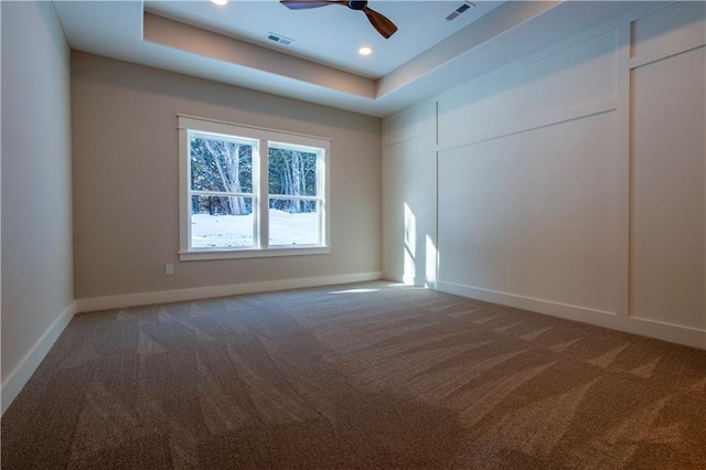 empty room featuring carpet floors, a raised ceiling, and ceiling fan