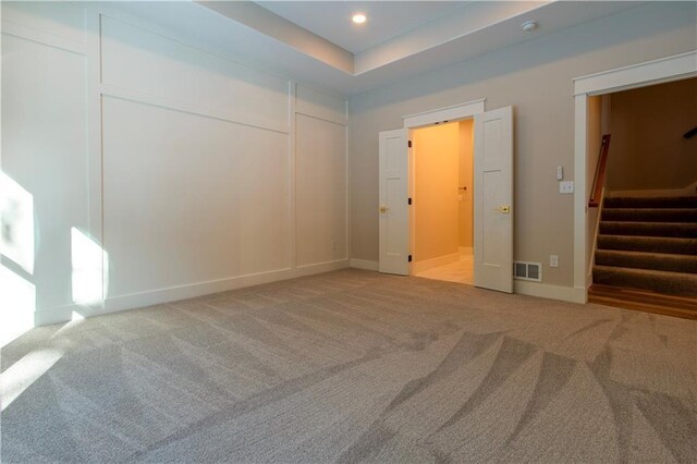 unfurnished bedroom with a closet, light colored carpet, and a raised ceiling