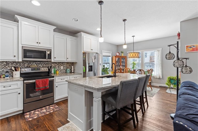 kitchen with sink, a center island with sink, white cabinets, stainless steel appliances, and backsplash