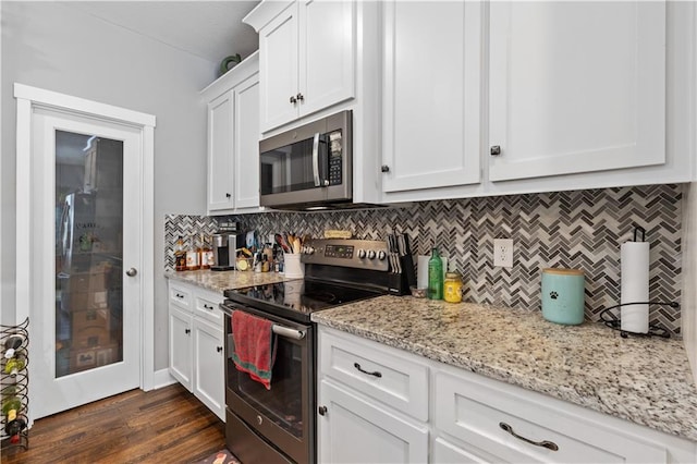 kitchen featuring white cabinetry, light stone counters, dark hardwood / wood-style flooring, stainless steel appliances, and backsplash