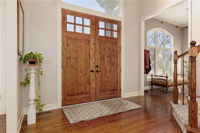 foyer entrance with ornamental molding and dark hardwood / wood-style floors