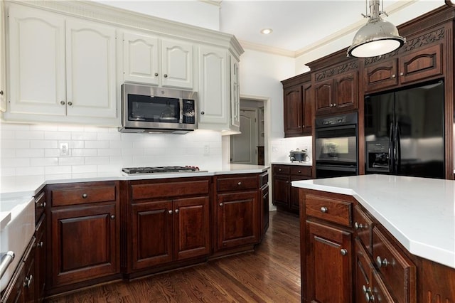 kitchen featuring pendant lighting, decorative backsplash, black appliances, crown molding, and dark wood-type flooring