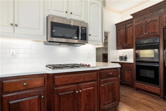 kitchen with crown molding, stainless steel appliances, dark hardwood / wood-style flooring, and tasteful backsplash