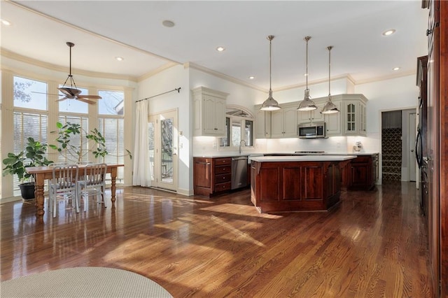 kitchen with appliances with stainless steel finishes, dark hardwood / wood-style floors, pendant lighting, tasteful backsplash, and a center island