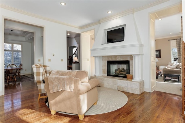 living room with hardwood / wood-style flooring, ornamental molding, and a tile fireplace