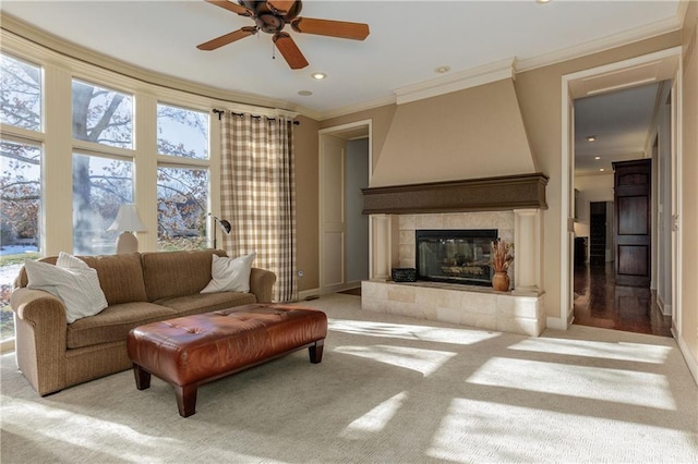 living room with a tiled fireplace, crown molding, and light colored carpet