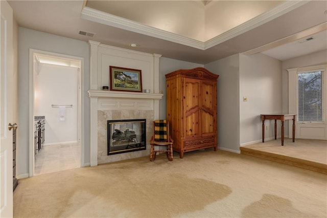 living room with crown molding, a tray ceiling, a tiled fireplace, and carpet floors