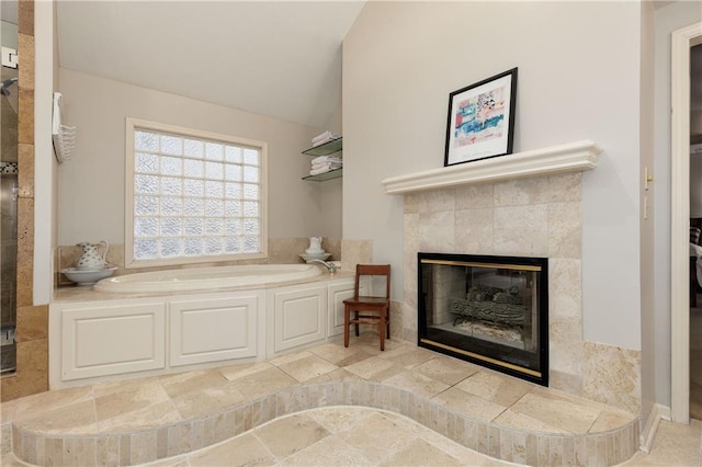 interior space featuring vaulted ceiling, a bath, and a fireplace