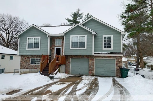 bi-level home featuring cooling unit and a garage