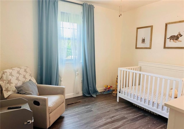 bedroom with dark wood-type flooring and a nursery area