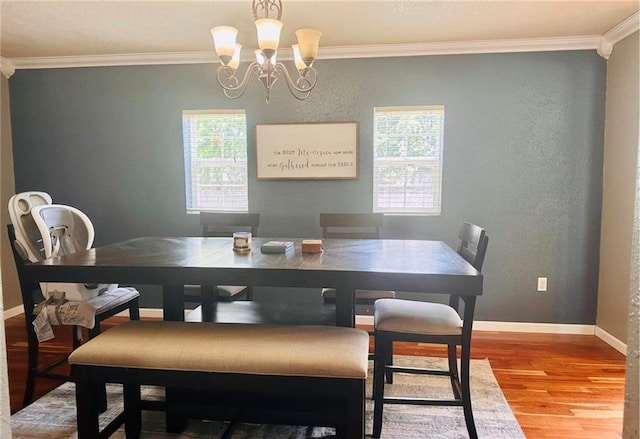 dining area with hardwood / wood-style flooring, ornamental molding, and a chandelier