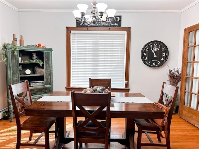 dining area featuring wood-type flooring, ornamental molding, and an inviting chandelier