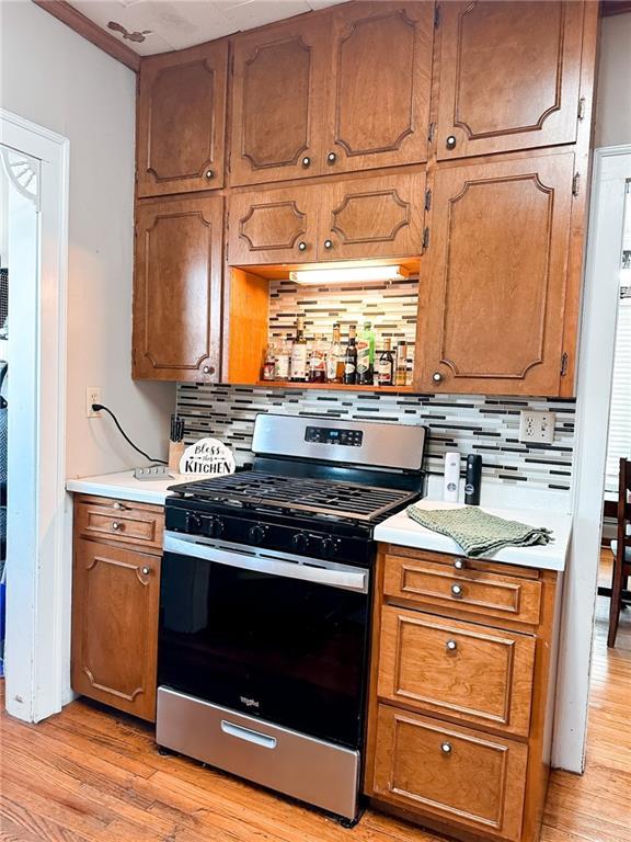 kitchen with decorative backsplash, light hardwood / wood-style floors, and stainless steel range with gas stovetop