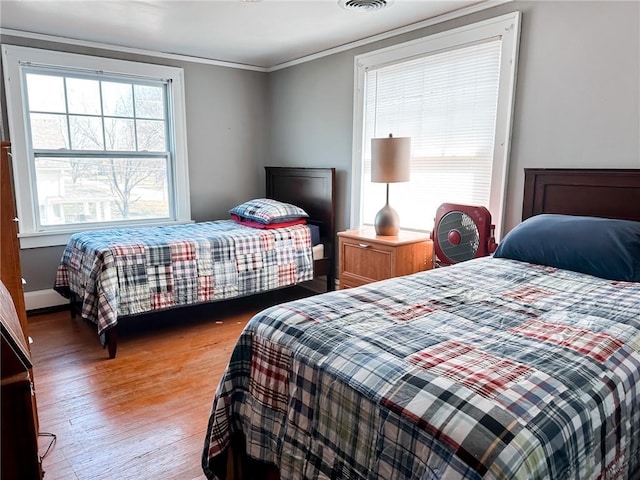 bedroom with multiple windows, hardwood / wood-style flooring, and ornamental molding