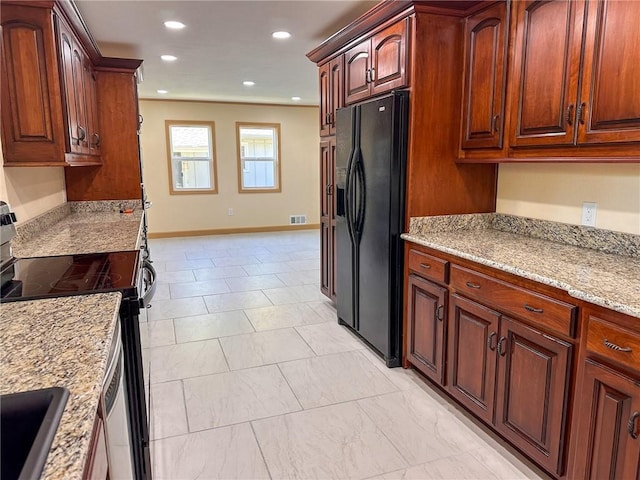 kitchen with electric range, black fridge, light stone countertops, and sink