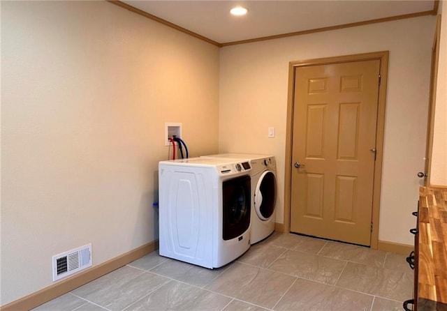 washroom featuring light tile patterned floors, crown molding, and washing machine and clothes dryer