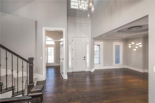 foyer featuring a raised ceiling, crown molding, dark wood-type flooring, and a high ceiling