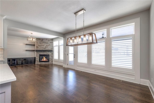 unfurnished living room featuring dark hardwood / wood-style floors and a stone fireplace