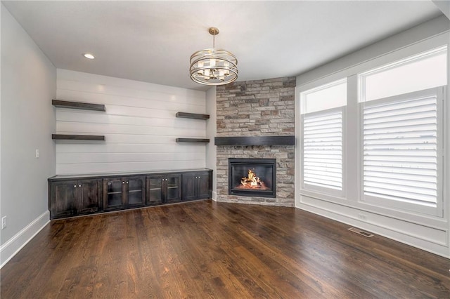 unfurnished living room with dark hardwood / wood-style flooring, a fireplace, and an inviting chandelier