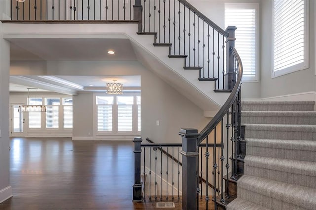 stairway with hardwood / wood-style flooring and an inviting chandelier