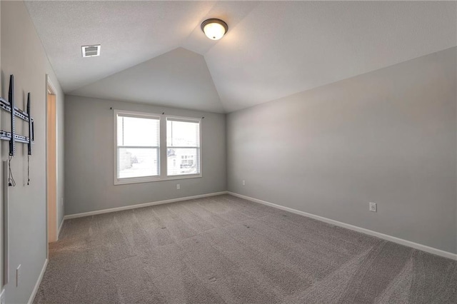 carpeted spare room with lofted ceiling