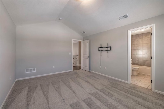 unfurnished bedroom with connected bathroom, light carpet, and lofted ceiling