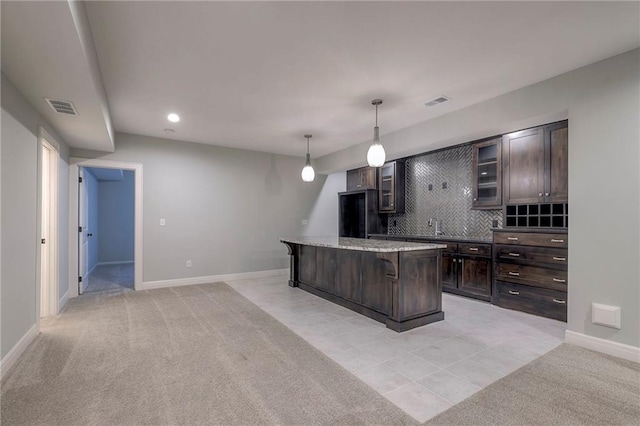 kitchen with tasteful backsplash, light colored carpet, decorative light fixtures, a breakfast bar area, and a kitchen island