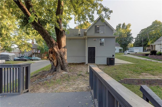 rear view of property featuring central AC and a yard