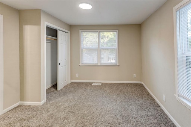 unfurnished bedroom with light carpet and a closet