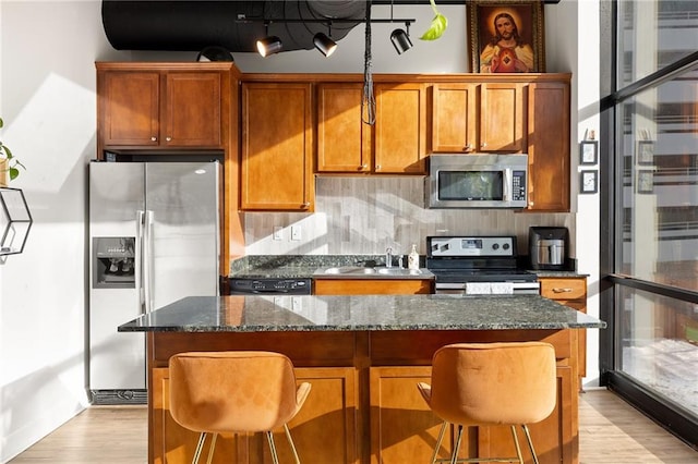 kitchen featuring a center island, sink, stainless steel appliances, backsplash, and a breakfast bar