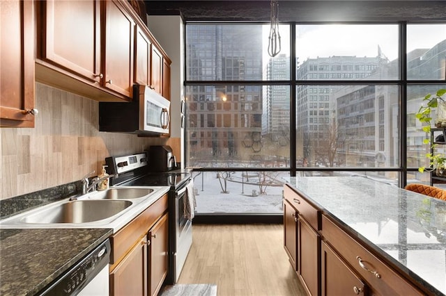 kitchen featuring appliances with stainless steel finishes, light hardwood / wood-style floors, dark stone counters, and sink