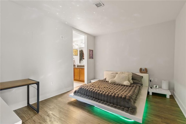 bedroom featuring connected bathroom and hardwood / wood-style flooring